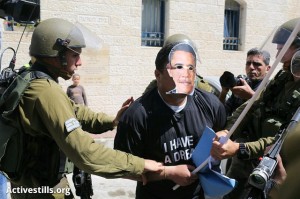 Demonstrant s maskou Baracka Obamy zadržený izraelskou armádou při protestu proti plánované návštěvě amerického prezidenta na Západním břehu Jordánu. Hebron, 20. března. (Foto: activestills.org)