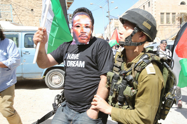 Demonstrant s maskou Martina Luthera Kinga zadržený izraelskou armádou při protestu proti plánované návštěvě prezidenta USA Baracka Obamy na Západním břehu Jordánu. Hebron, 20. března. (Foto: activestills.org)